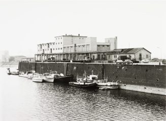 Binnenschiffe und Boote an einer Hafenbeckenmauer, vor dem Rhenania-Allgemeine-Gebäude im Hafen Düsseldorf