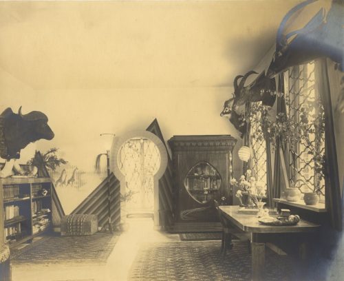 W. Hümmer (Künstler*in), Ohne Titel (Interieur der Wohnung eines Großwildjägers - Arbeitszimmer mit Bibliothek und mit Wandtrophäen), ca. 1910