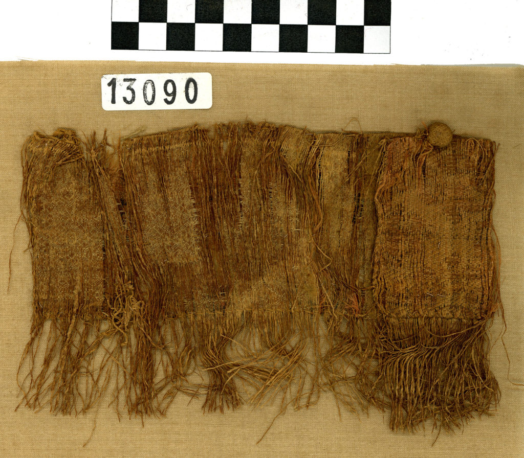 Gewebefragment (Ärmel?) mit textilem Knopf