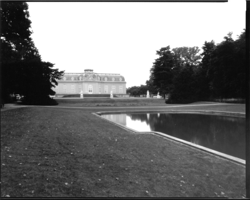 Die Südfassade von Schloss Benrath mit angeschnittenem Spiegelweiher über die Wiese westlich davon