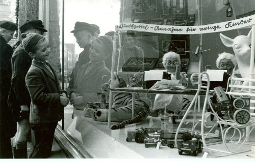 Dirk Alvermann (Fotograf*in), Strahlendes Kind vor weihnachtlicher Auslage eines Spielzeuggeschäftes, Düsseldorf, 1956