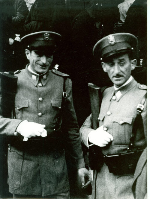 Dirk Alvermann (Fotograf*in), Kasernierte Bereitschaftspolizei Guardia Civil und Capuchones im Hintergrund, vereint zur Semana Santa, Tarragona, April 1957