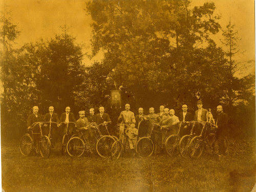 Unbekannt (Fotograf*in), Männergruppe eines Fahrradvereins mit Rädern und Vereinsfahne, ca. 1900