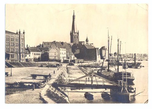 Julius Söhn (Fotograf*in), Rheinansicht mit St. Lambertus im Hintergrund sowie Schiffsanlegestellen in der unmittelbaren Nähe des Kohlentors, Ende 19. Jahrhundert